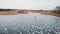 Aerial view. Winter fun on ice. A beautiful shot from a height, a woman rides on canyons on a frozen pond.