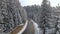 Aerial view of winter landscape with snow covered mountain woods and winding forest slippery road