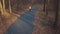 Aerial view of the woman running through an autumn forest at sunset