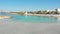 Aerial view woman tourist walk on beautiful Nissi beach in Cyprus. Famous travel visit destination. Popular famous white sand