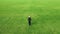 Aerial view of young adult woman walking on green grass rear view