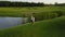 Aerial View Of Young Couple Walking In Summer Park, Circling Drone Shooting Man And Woman