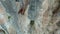 Aerial view of Young fit woman lead rock climbing on sport route on vertical cliff, outdoors rock climbing, cinematic