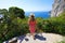 Aerial view of young tourist woman enjoying landscape from balcony in the Gardens of Augustus on Capri Island, Italy