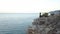 Aerial view of young woman on rock cliff against sea