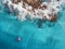 Aerial view of young woman swimming on the pink swim ring in the transparent turquoise sea in Maldives