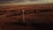 Aerial windmills producing sustainable energy at sunset with distant Canadian Rocky Mountains.