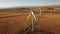 Aerial windmills turning cinematic shot over gravel county roads with distant Rocky Mountains.