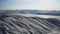 Aerial winter panorama. Frozen lake covered with ice. Snowy hills in sunshine.