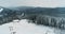 Aerial winter ski resort, snow forest peak slope. Trail and ski lift among trees. Beautiful panorama