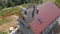 AERIAL: Workers lay red tin roofing sheets on a modern house under construction