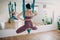 Aerial yoga concept. Woman practicing fly yoga in anti-gravity yoga studio using green hammock.