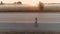 Aerial. a young girl is riding on a skateboard along a deserted highway at dawn