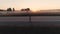 Aerial. a young girl is riding on a skateboard along a deserted highway at dawn