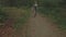 Aerial of a young woman walking through a forest, low altitude close tracking shot backwards then ascenting over her