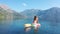 AERIAL. Young women enjoy floating on a mattress at the sea. Mountains on background.