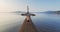 Aerial zooming out portrait of sportsman running along spit with lighthouse