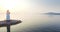 Aerial zooming out view of sportsman enjoying beautiful sun rise and calm sea