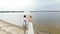 Aero, beautiful newlyweds walking along the beach, under a transparent umbrella, against the blue sky, river, and a