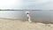 Aero, beautiful newlyweds walking along the beach, under a transparent umbrella, against the blue sky, river, and a