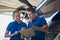 Aero Engineer And Apprentice Working On Helicopter In Hangar