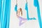 Aero fly yoga beautiful woman in uniform trainer shows asana stretching on blue hammock in white class