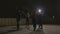 Aerobic class stretching led by a woman instructor in a dark underground cold place illuminated by lamps -