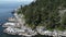 Aesthetic aerial shot of green rocky sea shore of pine trees and lighthouse port, Vancouver, Canada