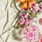 Aesthetic breakfast with croissant and pink flowers bunch on light green blanket at sunshine. Top view