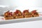 Aesthetic composition with shredded beef bruschetta on white background with shadows from flowers. Italian bruschetta with