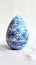 Aesthetic easter egg in traditional blue ethnic painting style. White background. Copy space. Generative AI