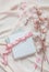 Aesthetic lifestyle with notebook, white box and pink ribbon on beige fabric background with cotton branches and pink petals. Top