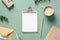 Aesthetic minimal office desk table with clipboard mockup, coffee cup, stationery and eucalyptus leaves on green background. Flat