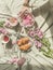 Aesthetic picnic at sun day with croissants, tea, bouquet of pink flowers and candles. Women hand holding glass vase with floating