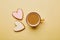 Aesthetics coffee cup and shape heart cookies. Spring card with baked glazed cookies on yellow background. Breakfast