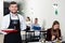 Affable male waiter is standing with order in luxury restaurante