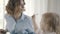 Affectionate baby in shirt eats herself at the table with her parents.