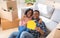 Affectionate black couple showing paper house and key to their home, sitting on floor of new property on relocation day