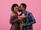 Affectionate black guy giving his sweetheart bouquet of flowers for Valentine`s Day and kissing her on pink background
