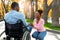 Affectionate black woman holding her paraplegic husband's hand, expressing love at autumn park