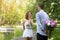 Affectionate boyfriend hiding bouquet of flowers for his beloved girlfriend behind his back at park, empty space