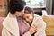 Affectionate cute little girl embracing her grandmother while resting on couch