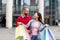 Affectionate interracial couple standing near mall with shopping bags, looking at each other, satisfied with purchases