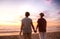 Affectionate lesbian couple holding hands watching a beach sunset