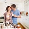 Affectionate man kissing his girlfriend while cutting bread for breakfast in the kitchen