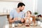 Affectionate pleasant looking father and his little daughter eat tasty morning meal at kitchen, communicate with each