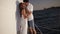 Affectionate young couple kissing and hugging each other while sailing on yacht. Standing next to the sail. Blue sea on
