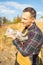 Affectionate young male farmer petting cat in countryside.