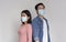 Afraid Asian Couple In Protective Medical Masks Over Light Studio Background