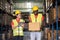 Africa American engineer woman holding tablet wearing safety helmet and vest standing in the automotive part warehouse. Looking at